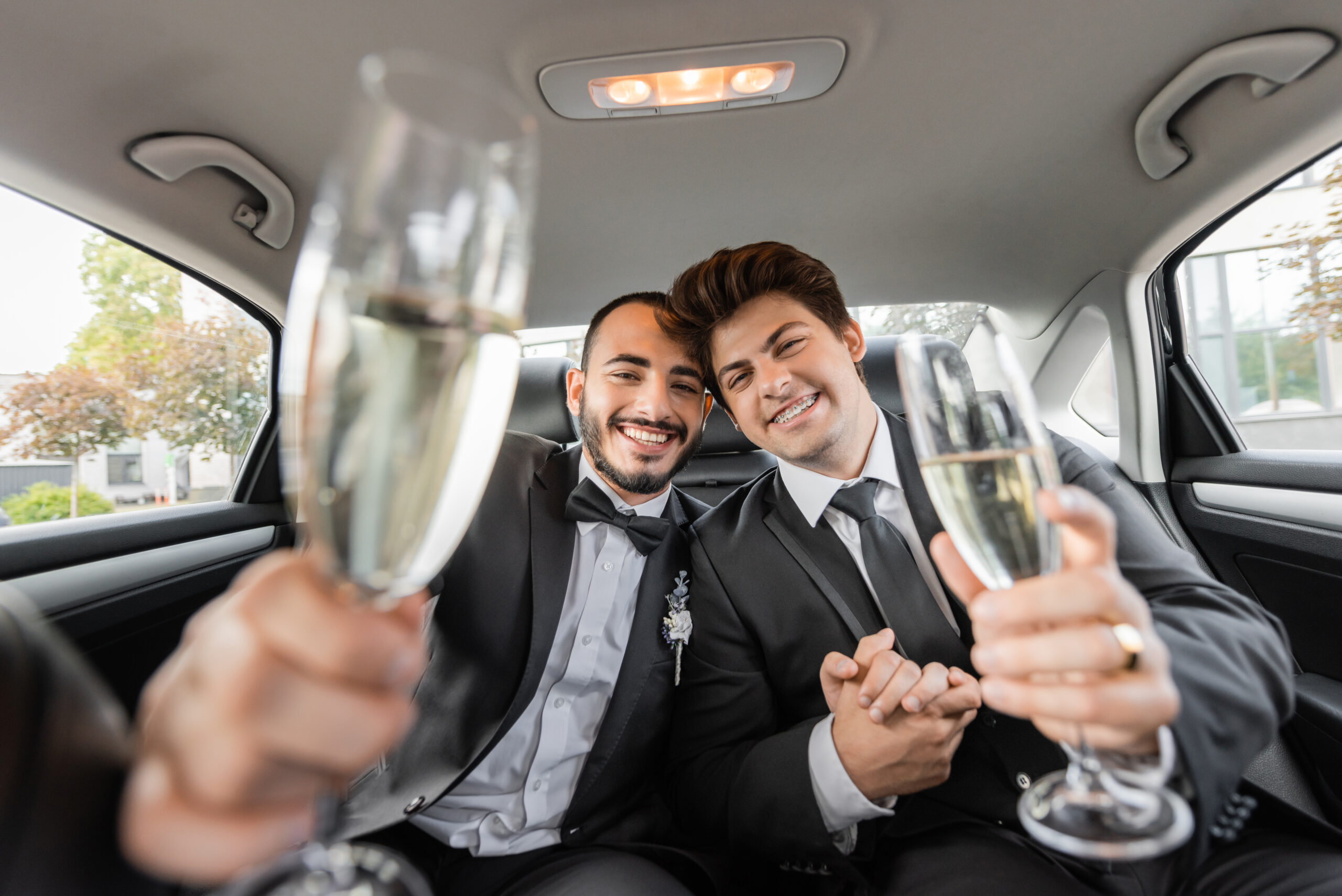 Un couple élégant célébrant leur mariage avec des coupes de champagne à l’intérieur d’une limousine.